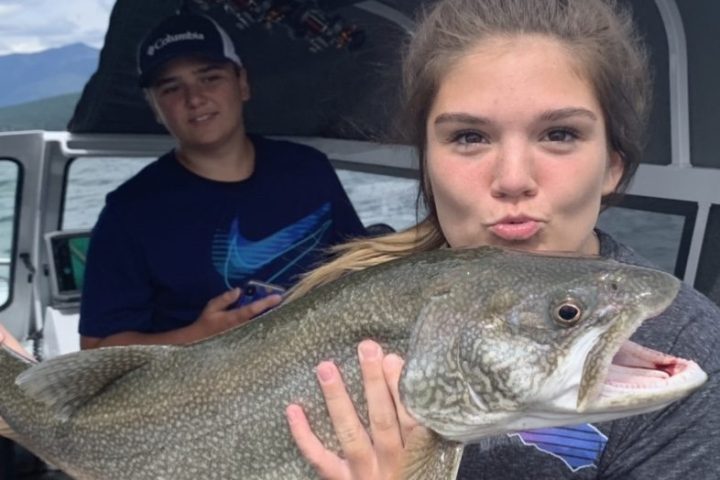 Woman holding a large fish on a boat, with a man in the background.