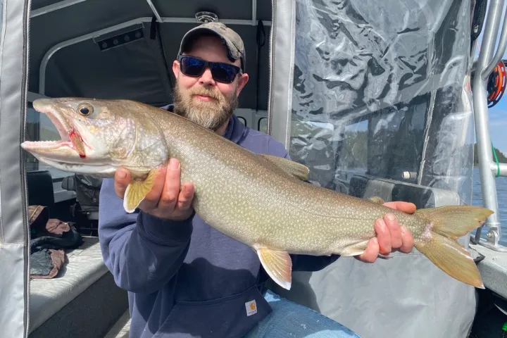 Person holding a large fish on a boat.