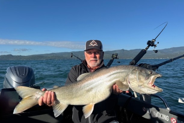 Man holding large fish on a boat in a lake.