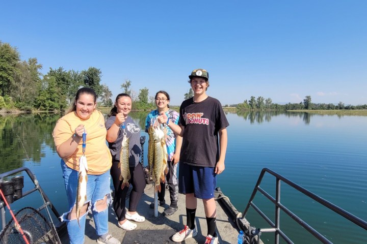 a person standing next to a body of water posing for the camera