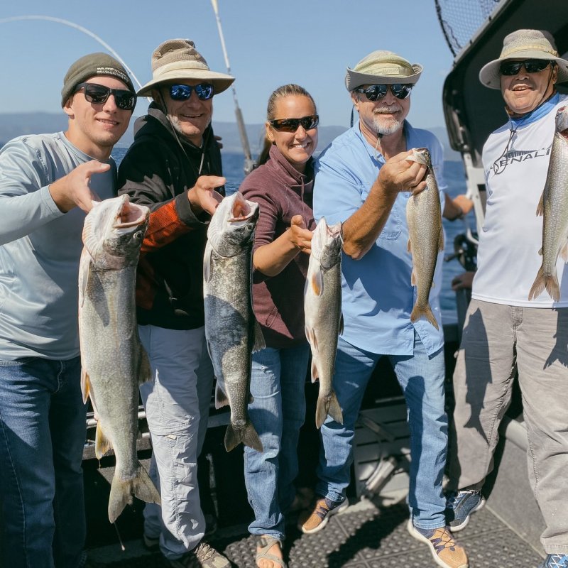 a group of people standing next to a man holding a fish