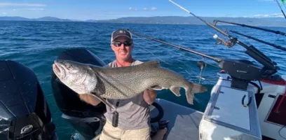 a man holding a fish on a boat in a body of water