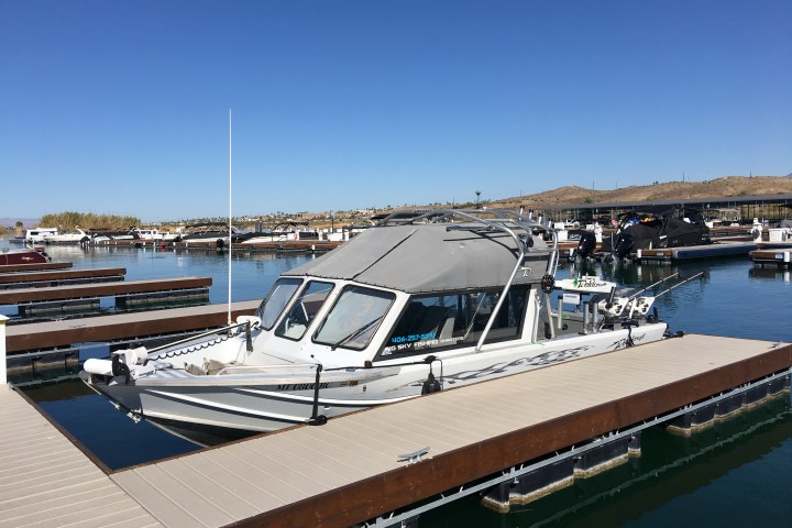 White boat docked at a marina with clear blue sky.